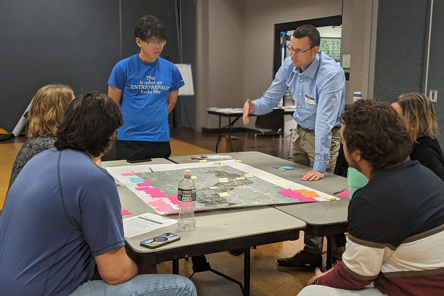 Small group gathered around a table with a map, listening to a facilitator